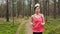 Woman running at forest trail and listening music from smart phone