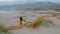 Woman running sandy dunes seashore at gloomy summer evening. Girl jogging desert