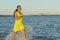 Woman running and splashing in the water at the beach. Young woman runs on water in sea. Beauty Young Girl In Holiday. In yellow