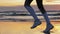 Woman running on sunset beach. Sport footwear, wet sand footprints