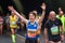 Woman runs marathon, arms raised, victory sign