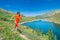 Woman runs in mountain path above a beautiful alpine lake