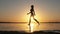 Woman Runs on Shallow Water at Golden Sunset along the Beach. Slow Motion 240fps