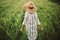 Woman in rustic dress and hat walking in green field of barley. Atmospheric authentic moment. Stylish girl enjoying peaceful