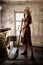 Woman in a rustic dress sweeps the wooden floor in the kitchen