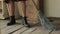 Woman in a rustic dress sweeps the wooden floor in the kitchen