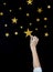 Woman`s arm catching paper bright stars in the night sky