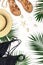 Woman`s beach accessories flat lay. Round trendy rattan bag straw hat black swimsuit leather sandals tropical palm leaves