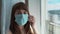 Woman`s face in protective medical blue mask, close up. Young female wearing medical mask for virus infection prevention