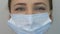Woman`s face in protective medical blue mask, close up. Young female wearing medical mask for virus infection prevention and prote