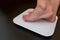 Woman`s feet standing on electronic scales for diet control