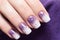 Woman\\\'s fingernails with purple and white colored nail polish design with golden stars