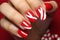 Woman\\\'s fingernails with red and white colored nail polish with seasonal Christmas themed design