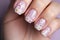 Woman\\\'s fingernails with white spring flowers on pastel pink base nail art design