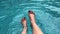 Woman`s foot playing water in blue water wave swimming pool