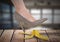 Woman`s foot about to step on banana peel and slip mistakenly on wood