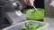 A woman's gloved hand removes foam from the wheatgrass juice with a spoon