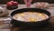 A woman`s hand adds seasoning to the shakshuka pan.