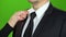 Woman`s hand adjusts the tie around her servant`s neck. Green screen. Close up