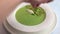 Woman's hand adorns cheese quenelle and sprigs of greens homemade soup puree