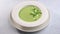 Woman's hand adorns sprigs of greenery homemade soup puree of green peas