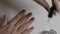 A woman`s hand applies a nail polish fixative to her nails. White background. Close-up on the fingers