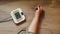 A woman`s hand with a blood pressure measuring device against the background of a wooden table. On the screen of the tonometer the