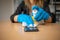 Woman& x27;s hand in blue gloves sanitizing cleaning smartphone mobile phone on wood table surface with wet wipes