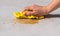 Woman`s hand cleaning spilled water on a cement floor with a yellow floor cloth dishcloth