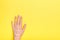 Woman`s hand in cream. Yellow background.