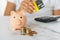 woman\\\'s hand with a credit card and a piggy bank, next to a calculator on the table. crisis and inflation. Cost