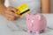 woman\\\'s hand with a credit card and a piggy bank, next to a calculator on the table. crisis and inflation. Cost