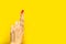 woman`s hand crosses fingers over bright yellow background