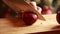 Woman\\\'s Hand Cutting Red Onion on Wooden Board CloseUp