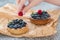 A woman`s hand decorates tartalets lying on mint paper with fresh raspberry berries.