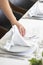 Woman\'s hand delicately folding a white cotton napkin, decorative technique adding an elegant touch to the table setup