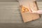 Woman`s hand doing happy thumbs up gesture over the last slice of pizza in the cardboard box on the wooden table in restaurant.