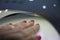 Woman`s hand drying her freshly polished nails under ultraviolet lamp in a nail salon in a beauty salon. Beauty concept