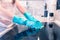 Woman`s hand in a glove cleans a black cooker panel