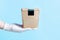 A woman`s hand in a glove holds a cardboard box with food, the concept food delivery