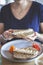 Woman`s hand grabbing a peanut butter, banana and strawberry toast on a table with fresh juice and coffee