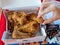 Woman`s hand grabbing piece of Popeyes Louisiana Chicken from dinner box in restaurant