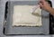 A woman`s hand greases a homemade pie lying on a baking sheet before baking.