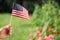 Woman`s hand holding an American flag in the backyard