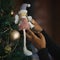 Woman`s hand holding a craft doll on a decorated christmas tree. Close up. Blurred background.