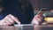 A woman`s hand holding credit card and pressing at mobile phone on wooden table in office