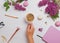 Woman`s hand holding a Cup of coffee on the table with beautiful lilac flowers