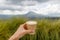 Woman`s hand holding a cup of coffee with a view of volcano Batur.