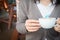 Woman`s hand holding a cup of redolent cappuccino coffee.