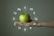 Woman`s hand holding green apple, microelement icons in molecular hexagons on grey background.